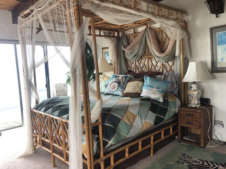 Master canopy bed with bamboo frame, sheer drapes and ocean-themed pillows