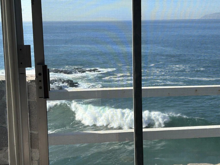 Ocean waves breaking below seen through living room sliding glass doors, like a view from a cruise ship deck
