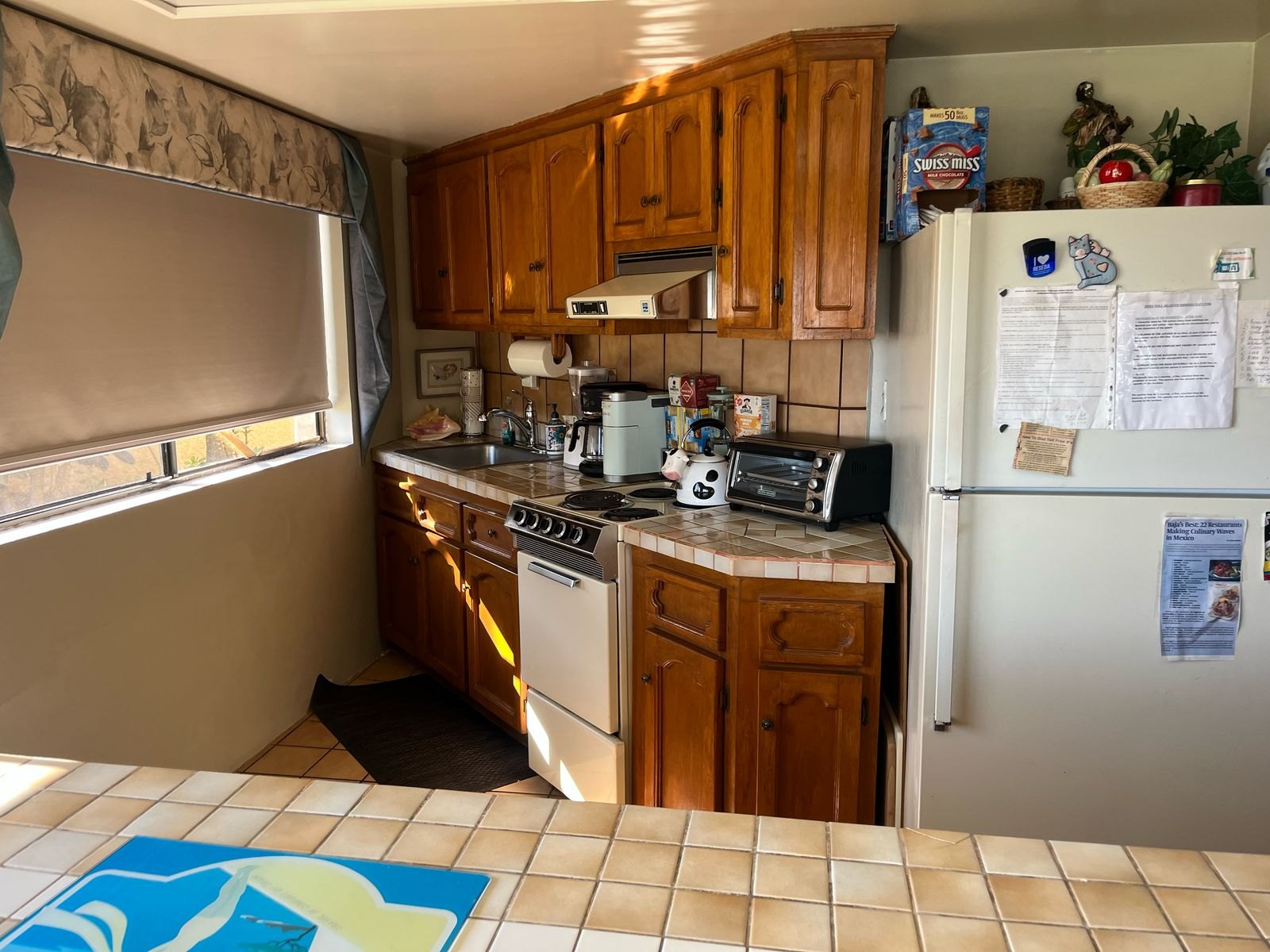 Kitchen with wood cabinets, tiled counters, electric range, refrigerator, coffee maker and toaster oven